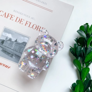 Detail of clear bear phone grip with colorful glitters and stars inside a transparent body