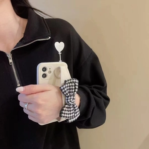 Detail of white iPhone case with houndstooth bow wrist strap and integrated hand grip