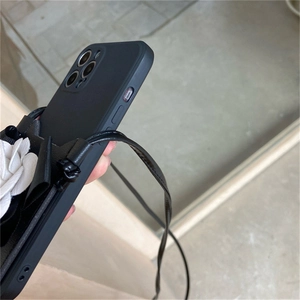 Detail view of black matte phone case with 3D white camellia and crossbody strap