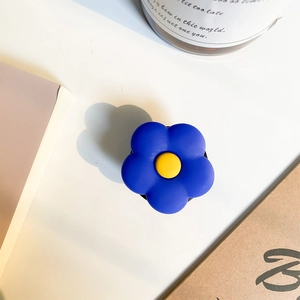 Supporto per cellulare a scomparsa fiore blu con centro giallo su scrivania bianca