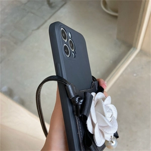 Detail of black leather iPhone case with white camellia flower and pearl pendant strap
