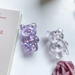 Close-up of bear-shaped phone grips with holographic sequins and glitter on white background