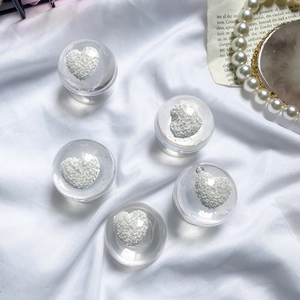 Detail of transparent resin phone grips with 3D white embossed heart inside on satin