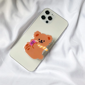 Close-up of a cute brown bear phone grip holder with soda pattern on a white phone