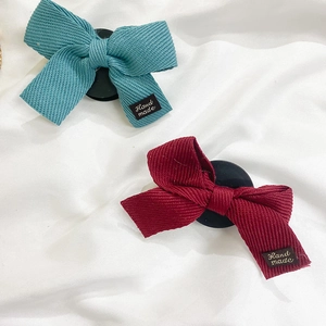 Détail de barrettes à nœud en tissu côtelé bleu et bordeaux avec étiquettes fait main
