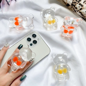 Detail of transparent bear phone sockets with cherry charms on a white fabric background