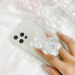 Close-up of pink and clear bear-shaped phone grip with ice crack texture on white phone