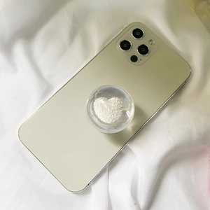 Close-up of a clear heart-shaped phone grip stand with white textured inlay on a smartphone