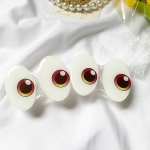 White cartoon eyeball hair clip on fabric with aesthetic jewelry and dry flowers