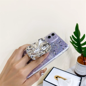 Détail de la main tenant une coque pailletée violette avec support en métal argenté