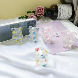Detail of transparent bear phone grips with real dried flowers on silk background