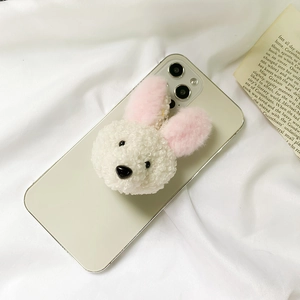 Close-up of white plush bunny phone socket on a white phone against a silk background
