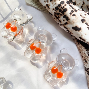 Detail showing three transparent bear-shaped phone grips with embedded orange cherry charms