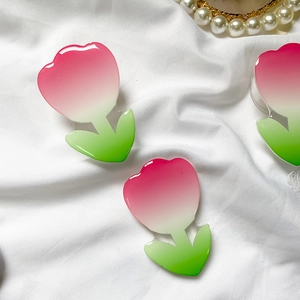 Detail shot of tulip phone grips with pink and green acrylic gradient on white fabric
