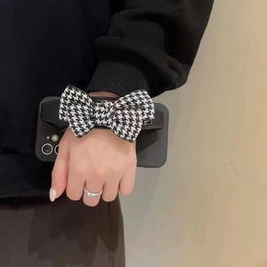 Matte black iPhone case with black and white houndstooth bow wristband holder