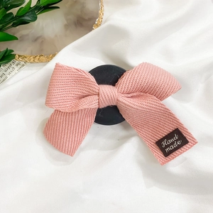 Détail d'un nœud en tissu rose fait main avec étiquette 'Hand made' sur une base noire