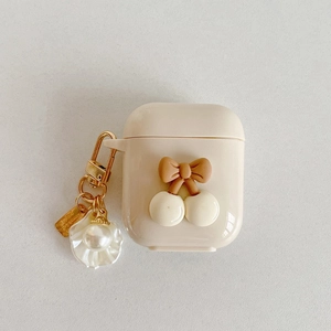 Detail of cream AirPods case with brown bow, cherry accent and pearl shell keychain
