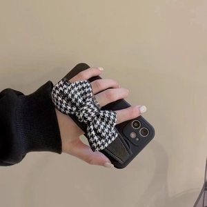 Chic iPhone case with a black and white houndstooth bow wrist strap for secure handling