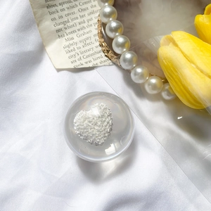 Detailed view of a transparent round phone grip featuring a white textured heart on silk