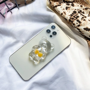 Detail of transparent bear phone grip with yellow cherries on a white smartphone