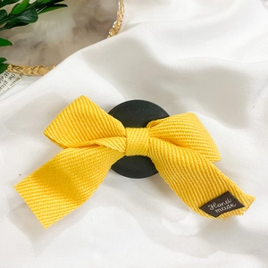 Détail d'un nœud papillon jaune fait main avec texture côtelée et étiquette tissée