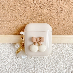 Detail of warm white AirPods case with cherry bow design and pearl floral keychain charm