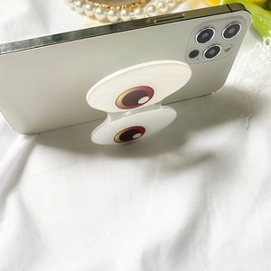 Close-up of eye-patterned expandable phone grip stand on a white smartphone