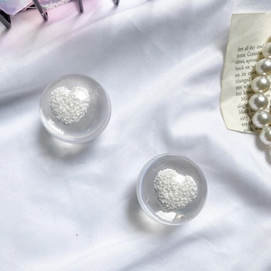 Detail showing two clear resin spherical grips with white 3D hearts on white fabric