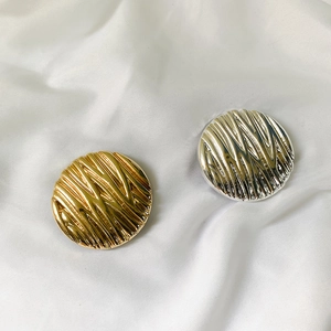 Detailed close-up of round gold and silver metal phone grips with wavy vertical texture