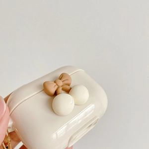 Detail of cream white AirPods case with brown bow, cherry charms and metal hook