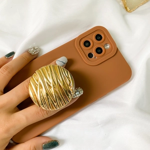 Close-up of caramel phone case featuring a premium gold water ripple pop socket grip