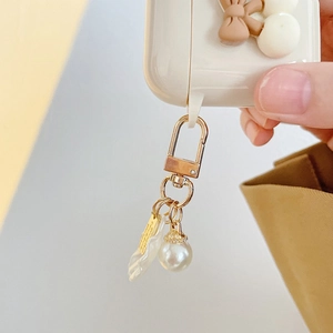 Detail of white pearl charm with gold clasp on AirPods case featuring a brown bow