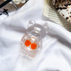 Macro shot of cute transparent resin bear phone stand with orange cherry decor