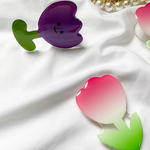 Close-up of cute tulip-shaped acrylic phone grip and holder with smile face on white fabric
