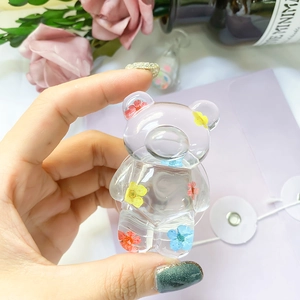 Macro shot of a transparent resin bear phone stand with embedded colorful dried flowers