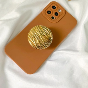 Detail of caramel silicone case with a golden wave-patterned metal phone socket grip