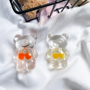 Detail of transparent bear phone grips with colorful cherry inserts on white fabric