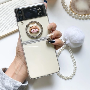 Detail view of Galaxy Z Flip case with pearl strap, pompom and rhinestone decor