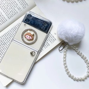 Close-up of clear Z Flip case with pearl strap, plush ball and cartoon ring charm