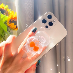 Transparent cartoon bear phone grip with cherry charms on a smartphone back