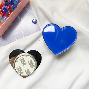 Detail of blue heart-shaped phone grip showing the high-quality 3M adhesive on metal base