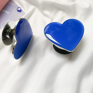 Macro view of blue heart phone grips with silver metal edges on white silk