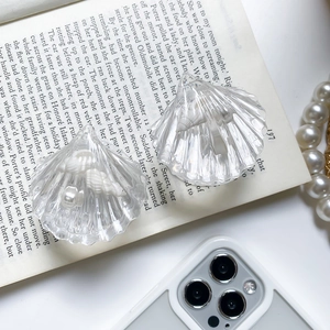 Macro view of clear seashell phone grip with faux pearls on an open book background