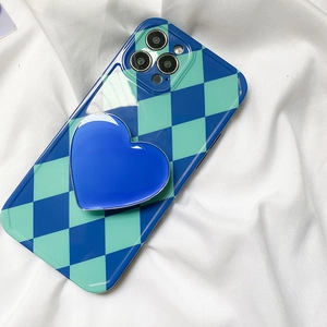 Close-up of heart-shaped phone grip and checkerboard case on white fabric