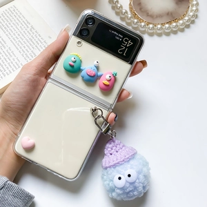 Detail view of Galaxy Z Flip case with 3D cartoon monsters and blue plush pendant charm