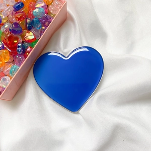 Detail of heart-shaped Klein blue phone grip with metallic silver trim on white fabric