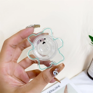 Cute transparent bear phone socket grip with green outline held in a person's hand