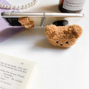 Gros plan détaillé du support téléphone ours peluche et breloques biscuit sur Z Flip