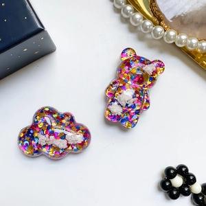 Dettaglio del supporto glitterato a forma di orso e nuvola con paillettes colorate e resina