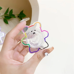 Transparent acrylic bear phone grip with rainbow outline held in hand for display
